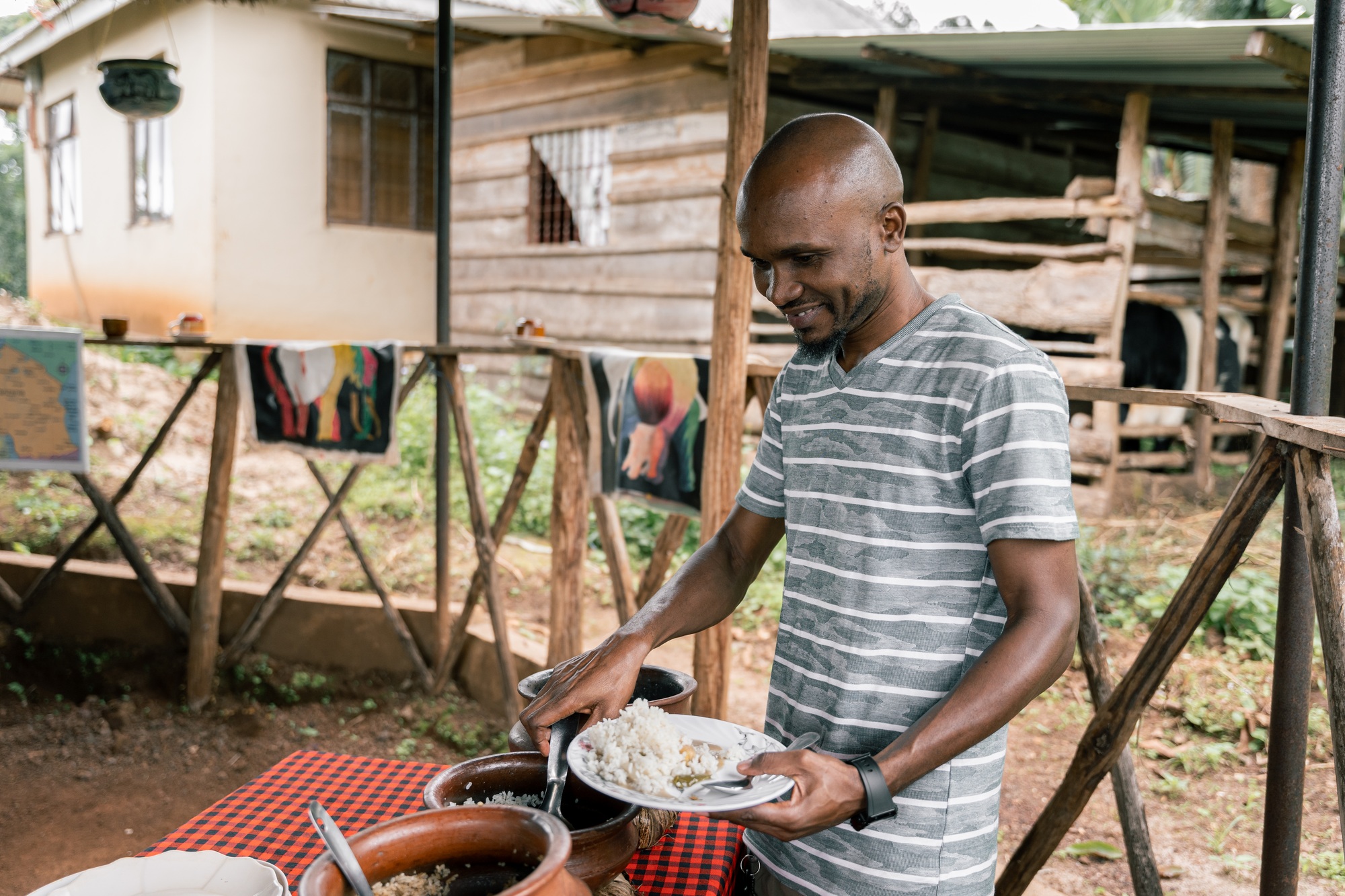African man smiling while plating traditional Tanzanian dish to serve